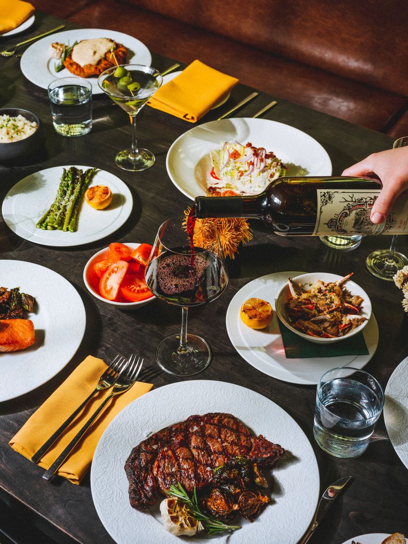 server pouring wine into a glass on a table full of incredible dishes at the Wellhouse at the Albert Hotel